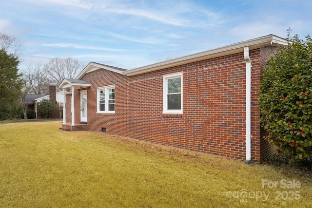 view of home's exterior with crawl space, brick siding, and a lawn