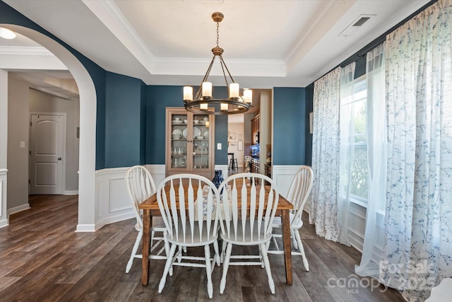 3216 Bridgewick Rd, Waxhaw, NC 28173 - dining area with a wainscoted wall, arched walkways, a chandelier, dark wood-type flooring, and a raised ceiling