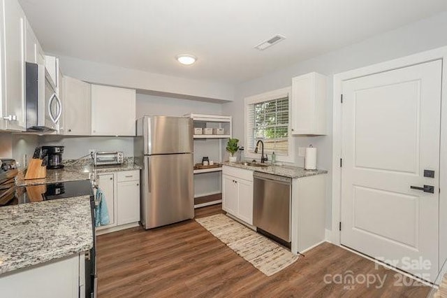 kitchen with appliances with stainless steel finishes, sink, white cabinetry, and light stone countertops