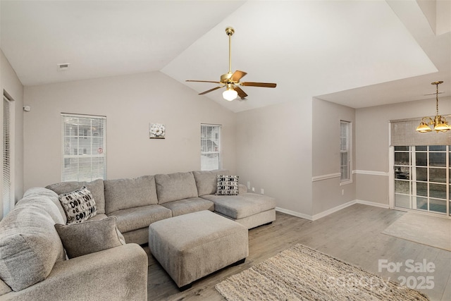 living room with vaulted ceiling, ceiling fan with notable chandelier, and light wood-type flooring