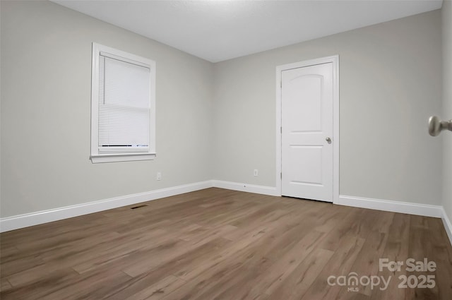 spare room featuring visible vents, baseboards, and wood finished floors