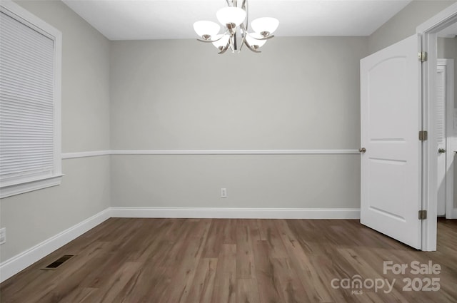 unfurnished dining area with a chandelier, visible vents, baseboards, and wood finished floors