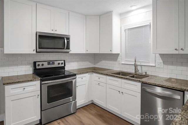 kitchen with appliances with stainless steel finishes, white cabinets, and a sink