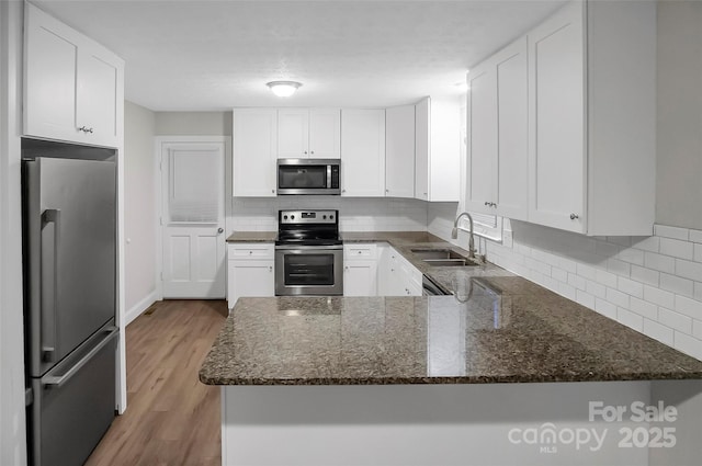 kitchen with dark stone countertops, decorative backsplash, stainless steel appliances, and a sink