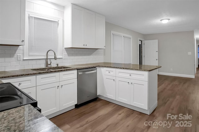 kitchen with a peninsula, wood finished floors, a sink, white cabinets, and dishwasher