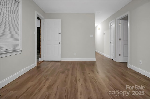 spare room with baseboards and wood finished floors