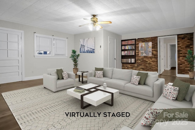 living area featuring brick wall, wood finished floors, a ceiling fan, and baseboards