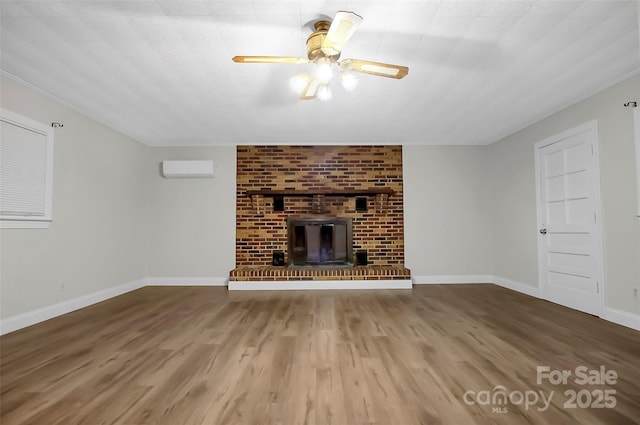 unfurnished living room with a ceiling fan, baseboards, wood finished floors, and a wall mounted air conditioner