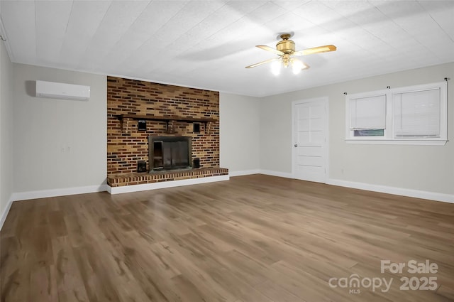 unfurnished living room with an AC wall unit, a fireplace, wood finished floors, and baseboards