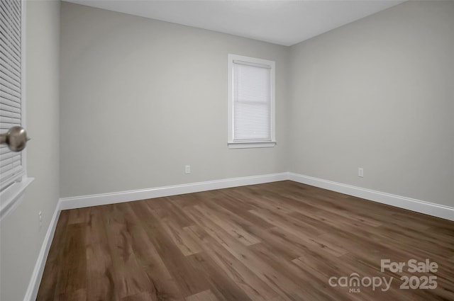 unfurnished room with dark wood-style flooring and baseboards