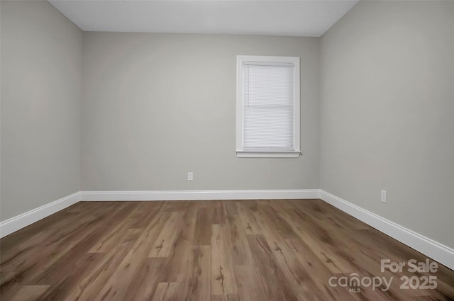 unfurnished room with baseboards and wood finished floors