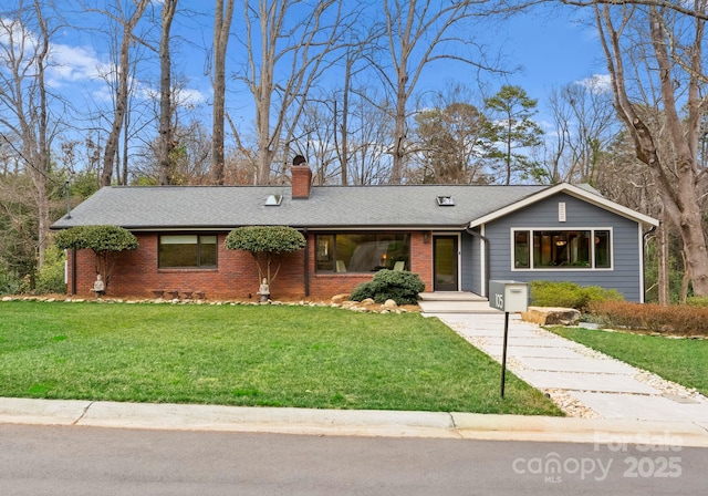 ranch-style home with driveway, roof with shingles, a front yard, brick siding, and a chimney