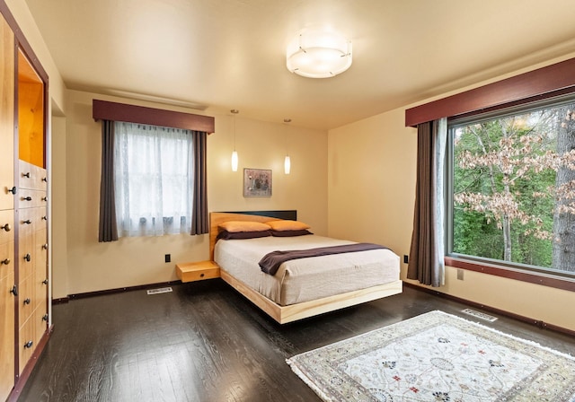 bedroom featuring visible vents, dark wood-type flooring, and baseboards