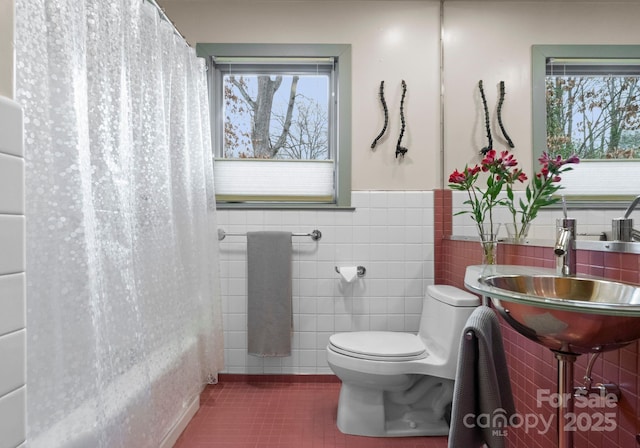 bathroom featuring a sink, wainscoting, tile walls, toilet, and tile patterned floors