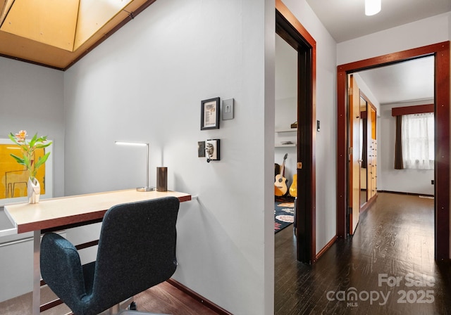 office space featuring built in desk, dark wood-type flooring, and baseboards