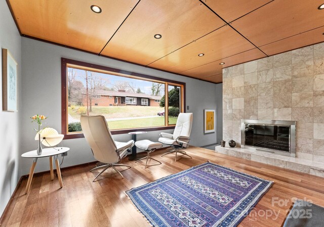 living area featuring baseboards, a tiled fireplace, wood ceiling, recessed lighting, and wood finished floors