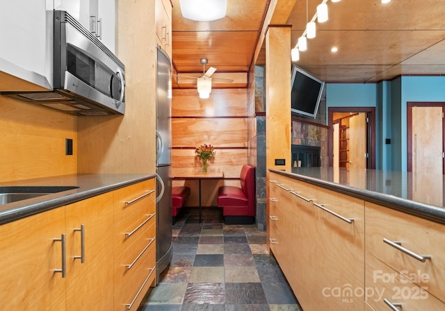 kitchen with stainless steel microwave, stone finish floor, and dark countertops