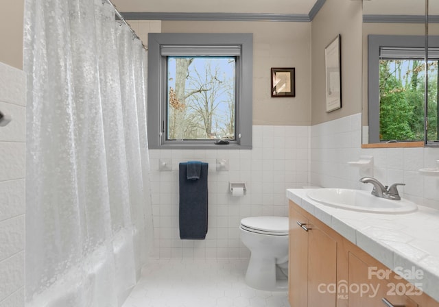 bathroom with vanity, ornamental molding, wainscoting, tile walls, and toilet