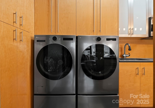 clothes washing area with cabinet space, washer and dryer, and a sink