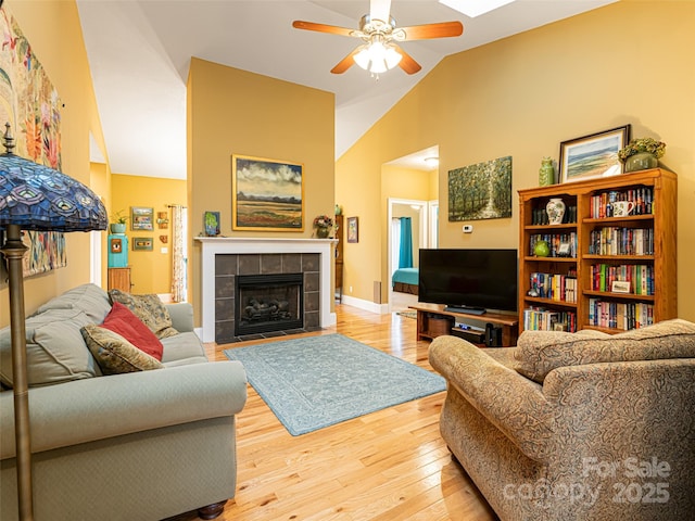 living room with a fireplace, hardwood / wood-style flooring, vaulted ceiling, and ceiling fan