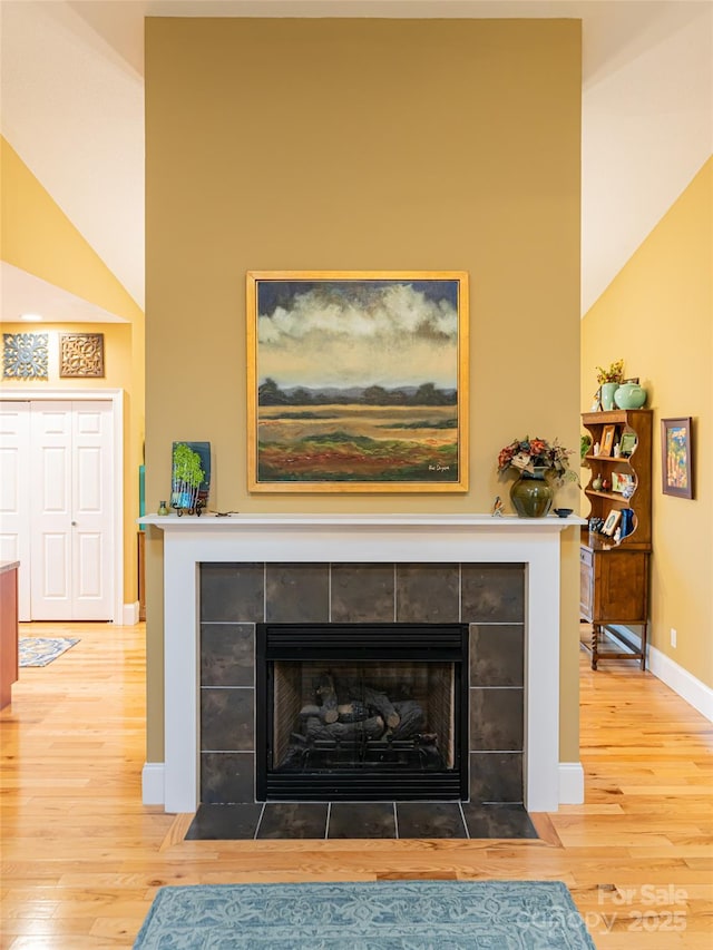 details with a tiled fireplace and hardwood / wood-style floors