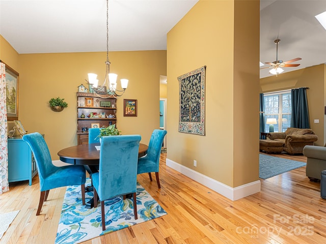 dining space with ceiling fan with notable chandelier and light wood-type flooring