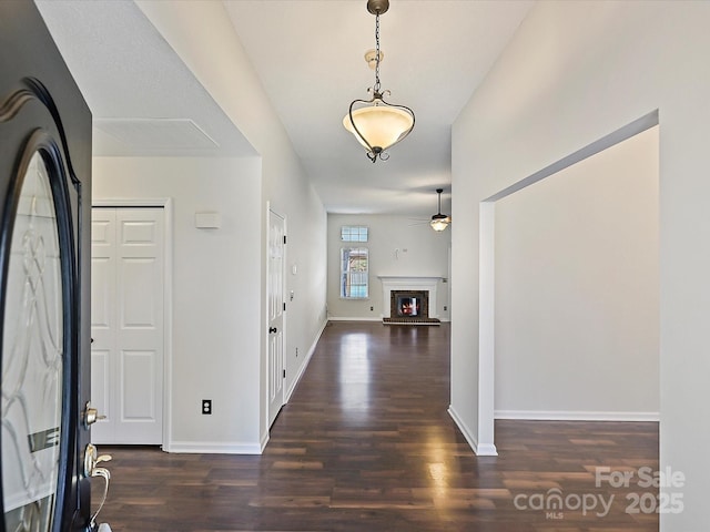 entryway with dark wood-style flooring, a fireplace, a ceiling fan, and baseboards