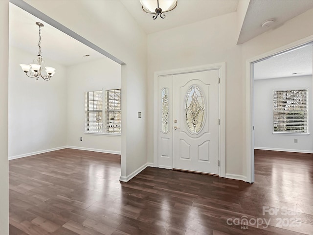 entryway with dark wood-type flooring, a chandelier, and baseboards