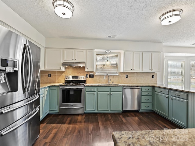 kitchen featuring visible vents, white cabinets, stainless steel appliances, under cabinet range hood, and a sink