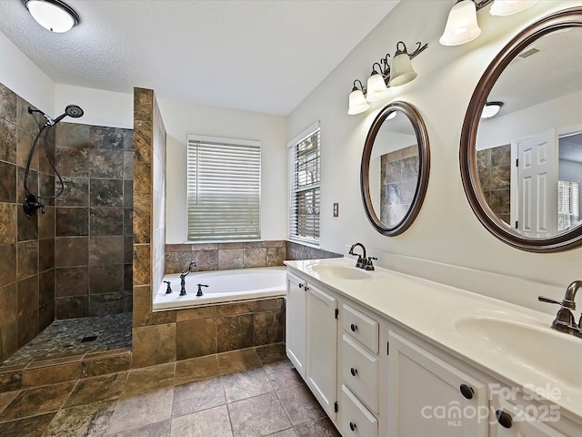 full bath with a garden tub, a textured ceiling, a sink, and visible vents