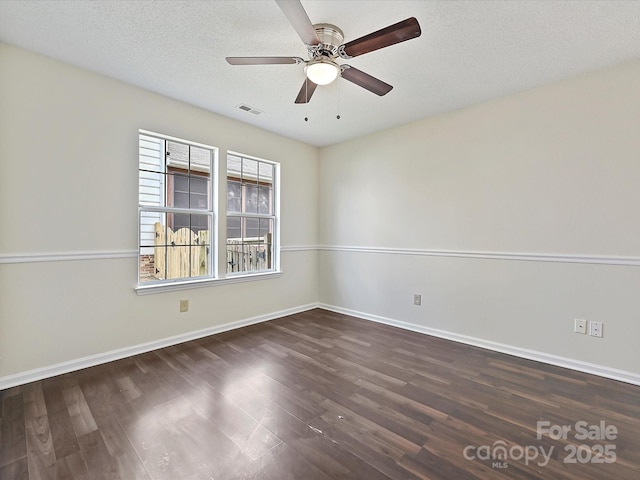 spare room with dark wood-style flooring, visible vents, a ceiling fan, a textured ceiling, and baseboards