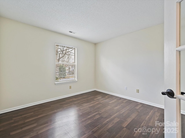 unfurnished room with dark wood-style flooring, visible vents, a textured ceiling, and baseboards