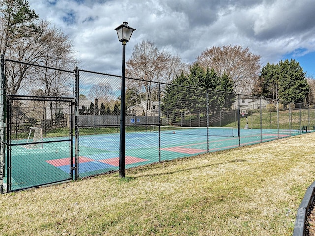 view of sport court featuring a gate, fence, and a lawn