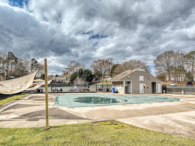 community pool featuring an outbuilding, a patio, and fence