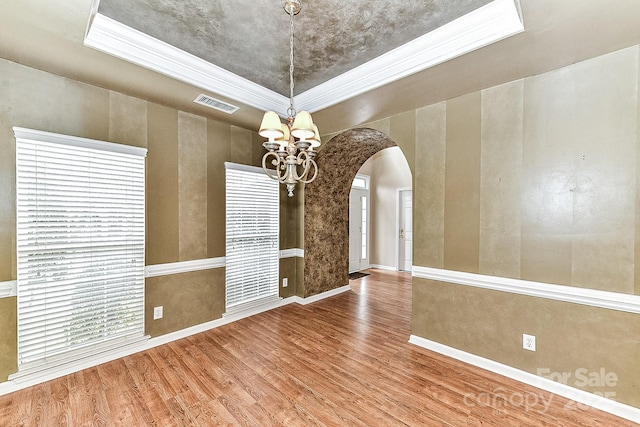 unfurnished room with ornamental molding, hardwood / wood-style floors, a notable chandelier, and a tray ceiling