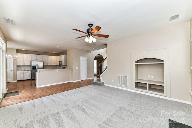 unfurnished living room featuring hardwood / wood-style floors and ceiling fan with notable chandelier