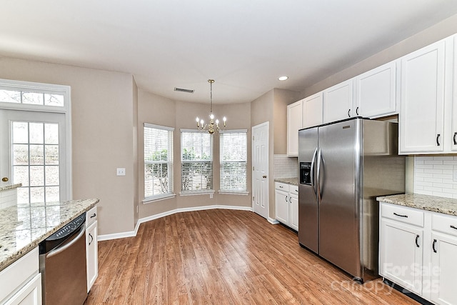 kitchen featuring hanging light fixtures, white cabinetry, appliances with stainless steel finishes, and light hardwood / wood-style flooring