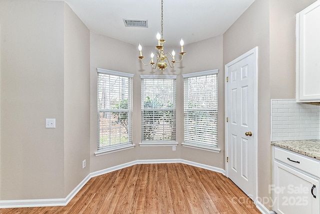 unfurnished dining area featuring a notable chandelier and light wood-type flooring