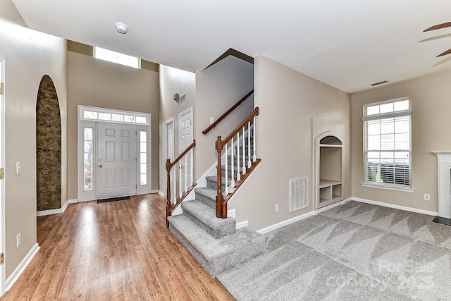 foyer entrance with hardwood / wood-style floors, ceiling fan, and a high ceiling