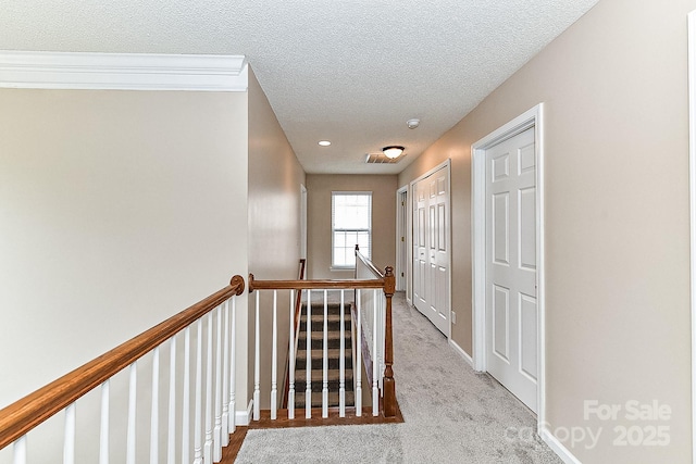 hallway with light colored carpet and a textured ceiling