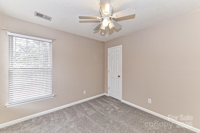 spare room featuring ceiling fan, carpet flooring, and a textured ceiling