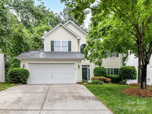 traditional home with a front lawn, driveway, a garage, and a chimney