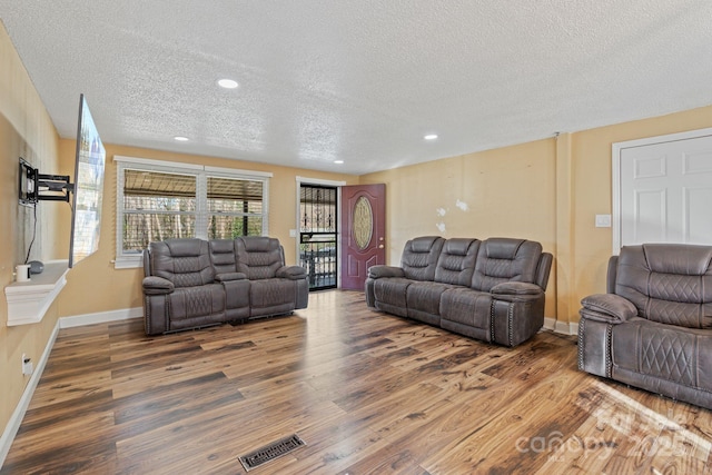 living room featuring wood-type flooring and a textured ceiling