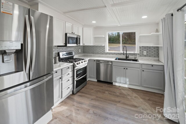 kitchen with light hardwood / wood-style flooring, sink, gray cabinetry, stainless steel appliances, and light stone countertops