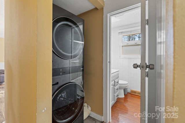 washroom featuring hardwood / wood-style flooring and stacked washer and dryer