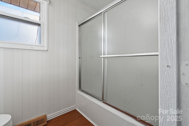 bathroom with ornamental molding, toilet, hardwood / wood-style flooring, and shower / bath combination with glass door