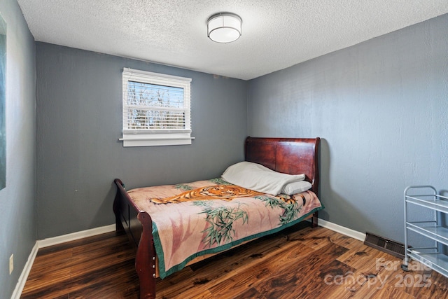 bedroom with a textured ceiling and dark hardwood / wood-style flooring