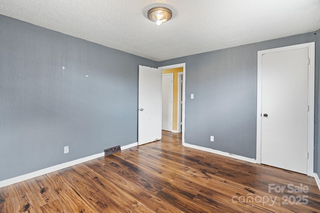 unfurnished room featuring a textured ceiling and dark wood-type flooring