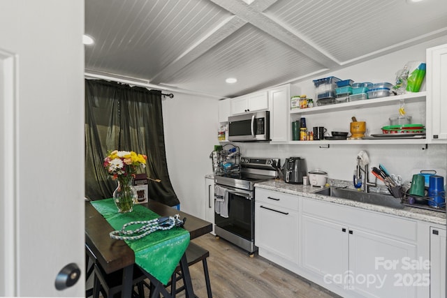 kitchen featuring appliances with stainless steel finishes, light hardwood / wood-style flooring, light stone counters, sink, and white cabinetry