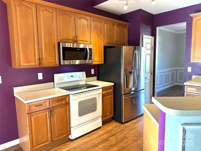 kitchen featuring crown molding, stainless steel appliances, and light hardwood / wood-style floors